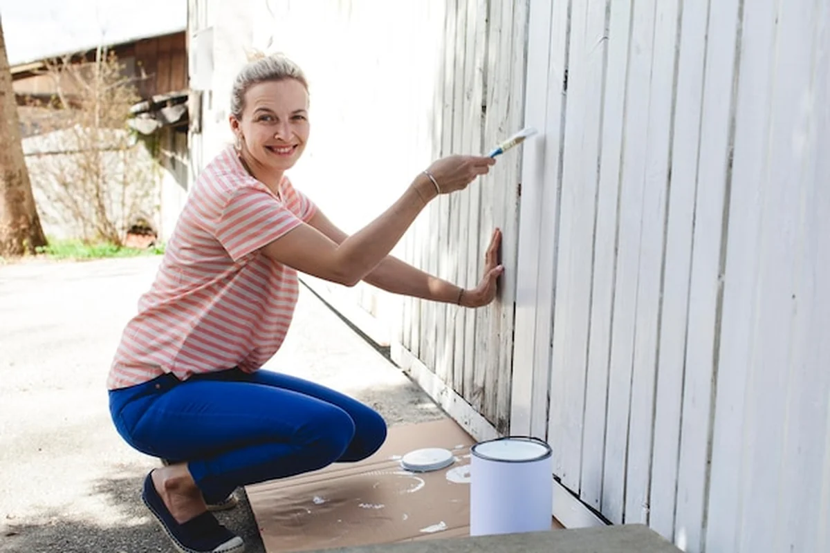 Kobieta malująca drewnianą ścianę