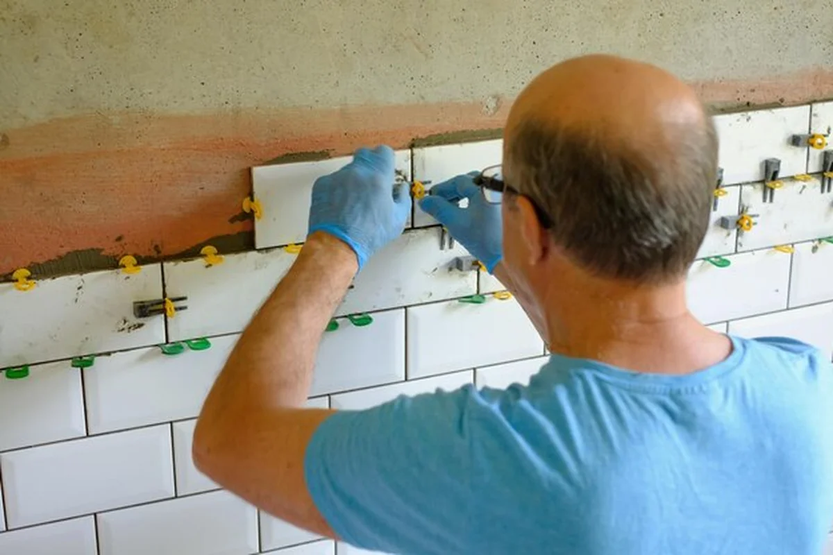 Pracownik układający płytki na ścianie w kuchni