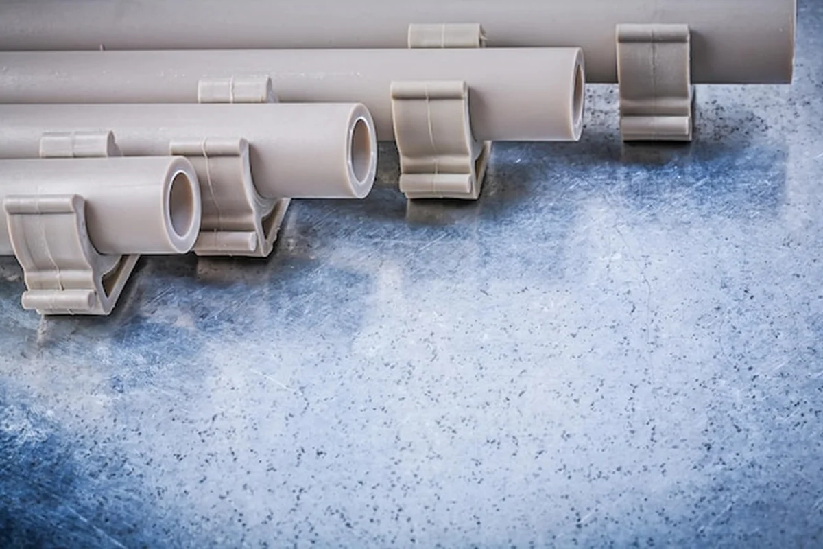 Plastikowe rury wodociągowe zaciski rurowe na metalicznym tle