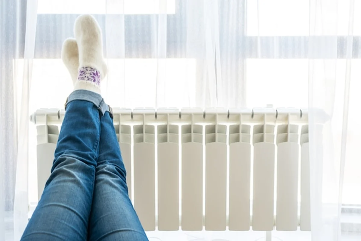 Kobieta na podłodze z nogami na grzejniku