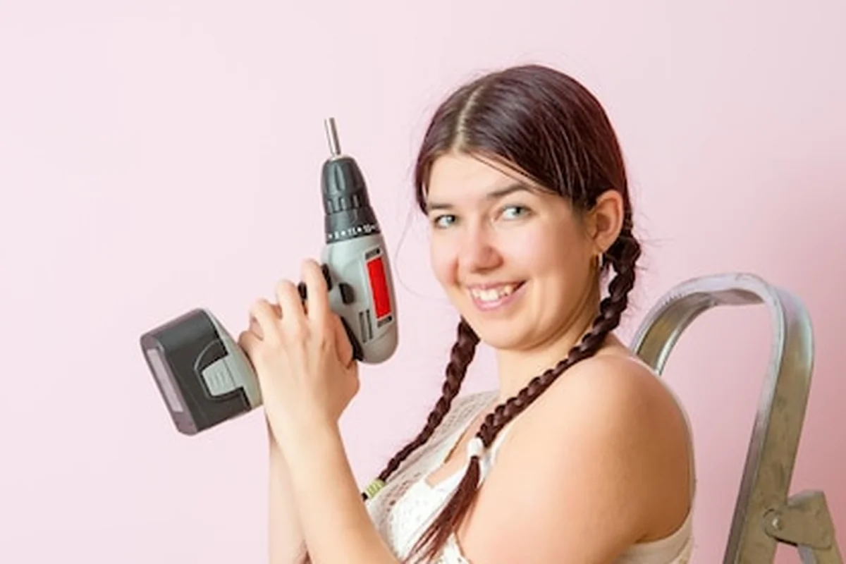 Szczęśliwa kobieta z wiertłem obok drabiny