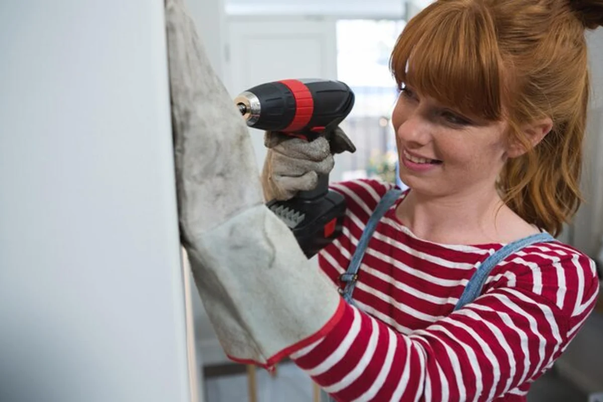 Kobieta stolarz używająca wiertarki