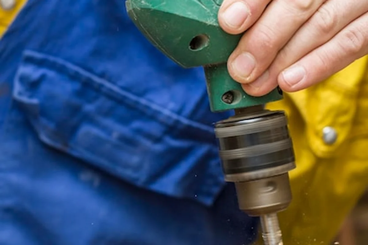 Stolarz wierci dziurę w drewnianych drzwiach za pomocą wiertarki